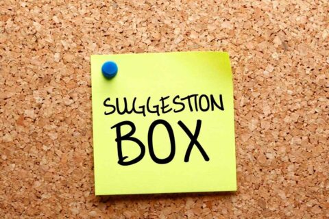 Post-it sur un tableau en liège avec écrit "Boite à suggestions" dessus